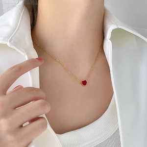 Close-up of a vibrant red heart-shaped gemstone pendant on a gold link chain necklace