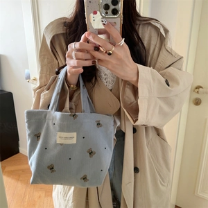 Blue corduroy tote bag with bear embroidery shown in a lifestyle mirror selfie