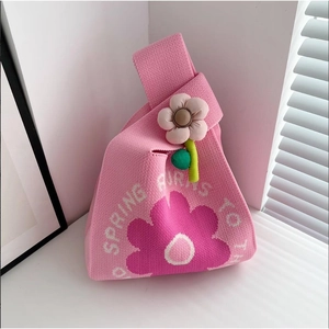 Close-up of pink knit handbag with floral pattern and 3D flower charm detail