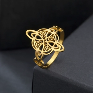 Golden stainless steel Celtic knot ring with intricate openwork design on a dark stand
