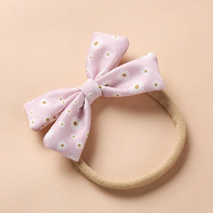 Detail of pink floral bow headband with white daisy print and soft nude nylon elastic