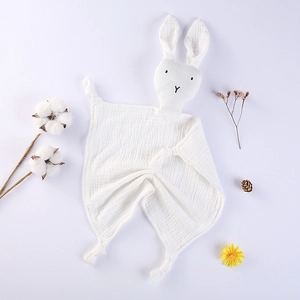 Détail d'un doudou en mousseline de coton blanc avec tête de lapin et coins noués pour bébé