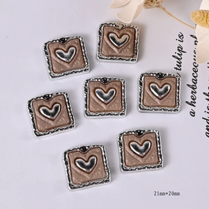Macro shot of 21mm retro silver heart charms with brown resin for DIY shoe decoration