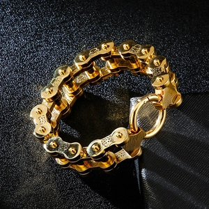 Close-up of golden bicycle chain bracelet with skull carvings on a dark textured background