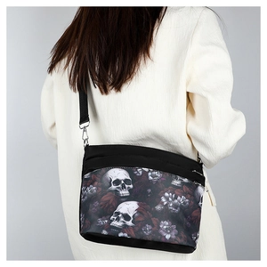 Close-up of gothic skull and floral print on a black crossbody bag worn by a model