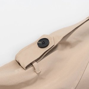 Detail of khaki twill jacket shoulder strap with black button and neat stitching
