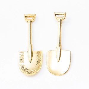 Macro shot of gold vintage shovel pendants featuring Russian artistic engraving