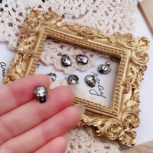 Detail of dark skull stud earring with faceted gunmetal finish and sparkling eye crystal