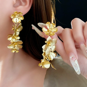 Gros plan sur des boucles d'oreilles fleurs dorées avec pétales et longues franges en métal