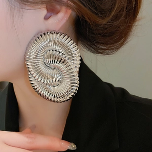 Detailed close-up of textured silver geometric spiral earrings worn on model for a bold look