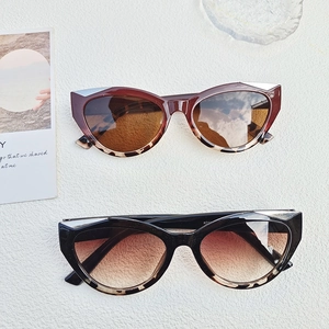 Close-up of Y2K cat-eye sunglasses in brown gradient and black amber on a textured surface