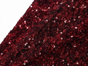Macro detail of wine red sequin fabric with dense circular sequins on a shiny V-neck dress