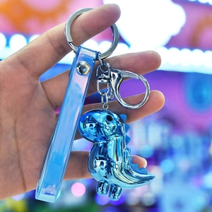 Blue chrome dinosaur keychain with translucent strap held in hand under neon light
