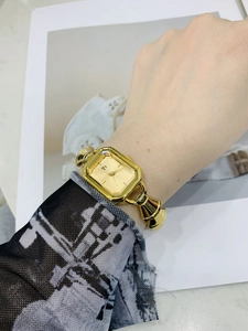 Primo piano di un orologio al quarzo dorato con quadrante quadrato e cinturino in metallo