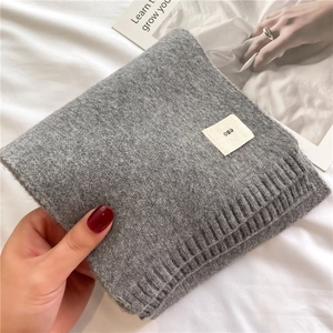Close-up of grey knitted wool scarf with Emo logo tag and ribbed edge texture