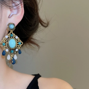 Detail of vintage bohemian earrings with turquoise stone and blue beads on model