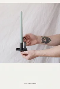 Detail of black metal candle holder with round base and ring handle in hand