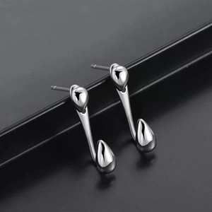 Macro shot of silver punk stud earrings with streamlined droplet design and mirror finish