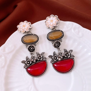 Close-up of vintage floral drop earrings with red stone and amber resin on ceramic plate