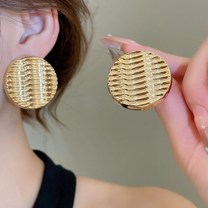 Detail shot of large golden ripple textured acrylic earrings showing metallic surface