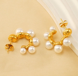 Detailed macro view of vintage C-shaped gold-plated earrings with five white pearls