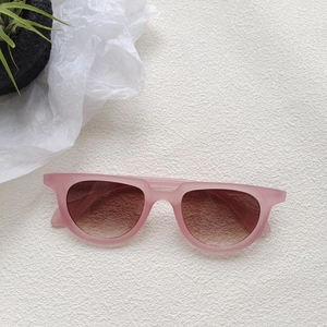 Pink matte sunglasses with brown gradient lenses on a minimalist white textured backdrop