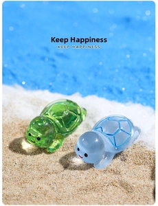 Close-up of cute green and blue resin sea turtle figurines on a sandy beach setting