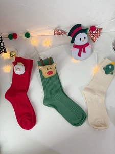 Flat lay of festive Christmas cotton socks with Santa, reindeer and tree plush patches