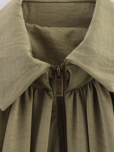 Gros plan sur le zip métallique et la texture du tissu du blouson bomber kaki