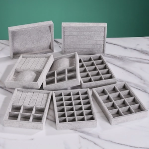 Gray velvet jewelry trays for rings and earrings on white marble surface