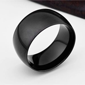 Close-up of a wide black polished stainless steel ring with a smooth mirror finish