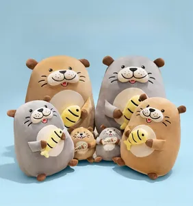 Close-up of cute plush sea otter toys in grey and brown holding small yellow fish