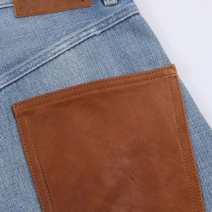 Detailaufnahme einer blauen Denim-Jeans mit brauner Ledertasche und aufgenähtem Label
