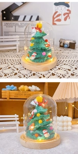 Detail of handcrafted crochet Christmas tree with LED lights in a glass dome on wood base