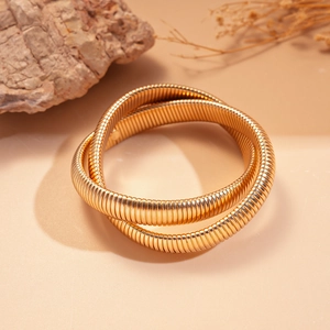 Detailed view of golden twisted spiral metal bracelet set on natural stone background