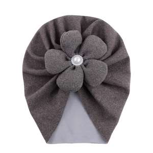 Detailed close-up of brown baby turban hat with large pearl flower decoration