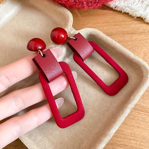 Detailed view of red geometric earrings with vintage leather texture and polished top beads