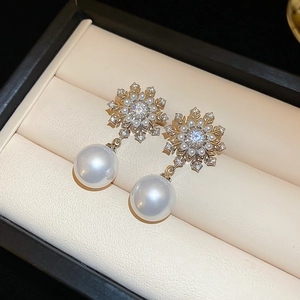 Macro view of snowflake earrings with sparkling zircons and a white pearl drop