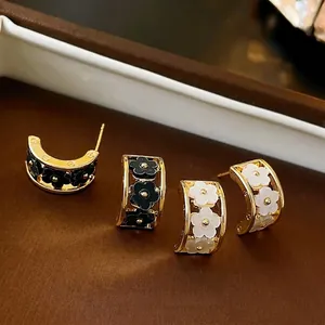 Elegant C-shaped flower earrings in black and white finish with gold metal details