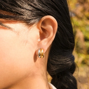 Detail of a woman wearing double-layer C-shaped two-tone stainless steel hoop earrings