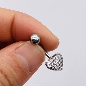 Detailed close-up of heart-shaped stainless steel belly ring with clear zircon crystals