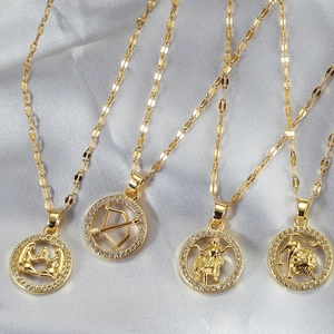 Gold-plated zodiac pendant necklace set with micro-paved zircons on grey silk fabric