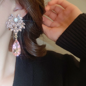 Détail de boucles d'oreilles argentées avec cristaux roses en forme de poire sur modèle