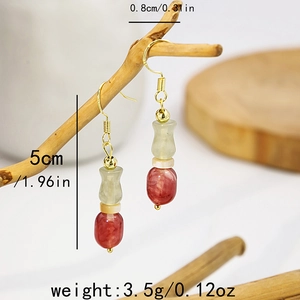 Detail of beaded tassel earrings with green gourd bead and red accent on a branch