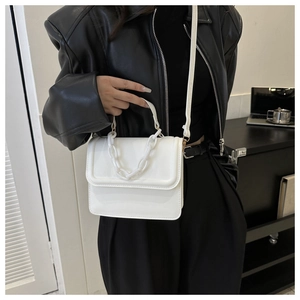 Detail showing white square crossbody bag with thick chain handle on a model
