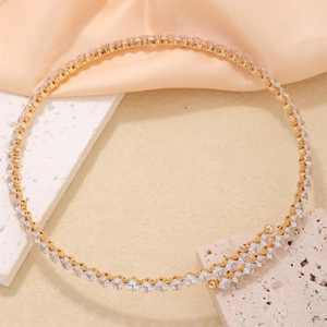 Detailed view of gold necklace with zircon stones on a peach silk fabric backdrop