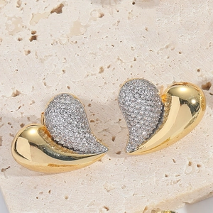 Macro shot of two-tone heart stud earrings with sparkling cubic zirconia on stone base