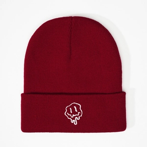 Detail of burgundy knit beanie featuring a white embroidered melting smiley face pattern