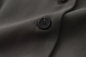 Vue macro de la texture du tissu gris foncé avec un bouton à quatre trous assorti