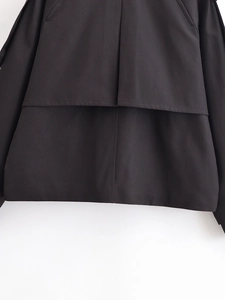 Detail view of the black trench coat back hem featuring a double-layered structure